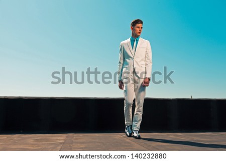Vintage summer fifties fashion man wearing white suit and tie. On rooftop. Blue sky.