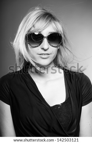 Beauty portrait of pretty girl with long blonde hair and sunglasses. Black and white shot.