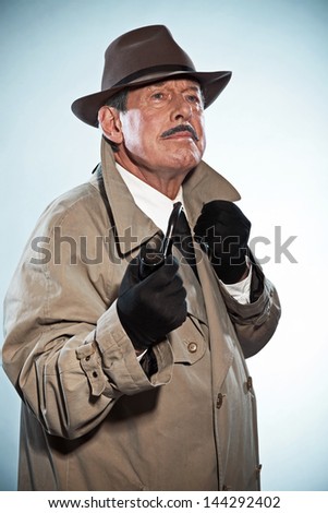 Vintage detective with mustache and hat. Smoking pipe. Studio shot.
