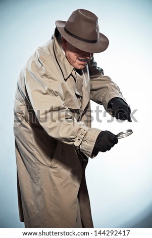 Vintage detective with mustache and hat. Looking through magnifying glass. Studio shot.