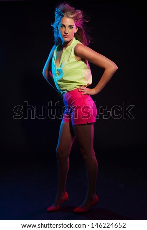 Sexy retro 80s fashion disco girl with long blonde hair and green shirt. Black background.