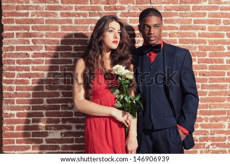 Urban cool vintage fashion mixed race wedding couple wearing black suit and red dress.
