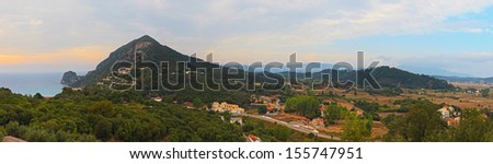 Panoramic shot of coastal landscape with mountains and blue cloudy sky. Greece. Corfu island.