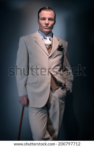 Retro 1920 business fashion man wearing white striped suit and tie. Standing with cane. Studio shot.