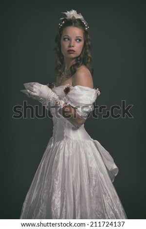 Victorian fashion woman wearing white dress. Holding porcelain tea cup. Studio shot.