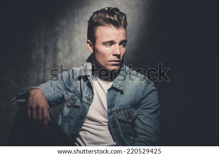 Retro fifties cool fashion man wearing white shirt and jeans jacket. Gray wall.