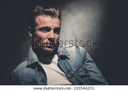 Retro fifties cool fashion man wearing white shirt and jeans jacket. Gray wall.