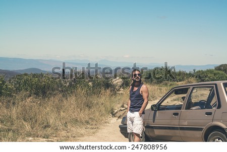 Man with sunglasses and long blonde hair standing next to car. Swartberg. Western Cape. South Africa.