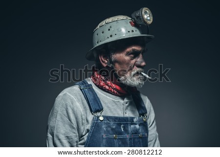 Close up Bearded Elderly Male Gold Miner Smoking a Cigarette While Facing to the Right of the Frame Against Black Gradient Background