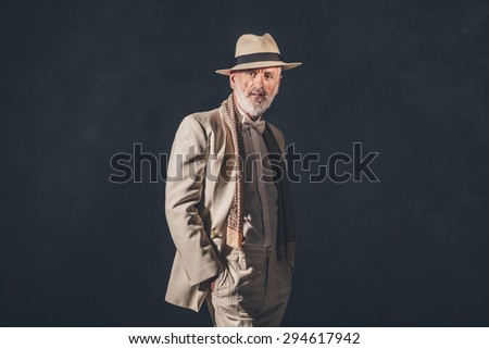 Portrait of a Stylish Matured Bearded Man Wearing Formal Fashion, Smiling at the Camera on a Black Wall Background.