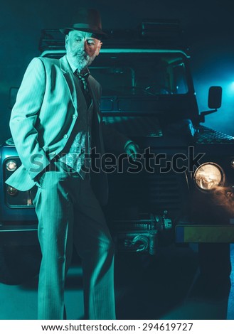 Elegant Middle Aged Man Leaning Against the Front of his 4x4 Vehicle with Pensive Facial Expression in the Middle of the Night.