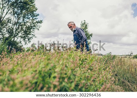 Middle Aged Bearded Male Farmer Looking at the Small Plants Growing on the Farm in the Morning.