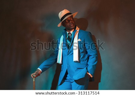 African american dandy man in blue suit and straw hat. Holding cane.
