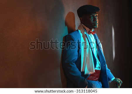 Retro african american man in blue suit wearing blue cap. Standing with cane.