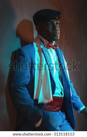 Retro african american man in blue suit wearing blue cap. Standing with cane.