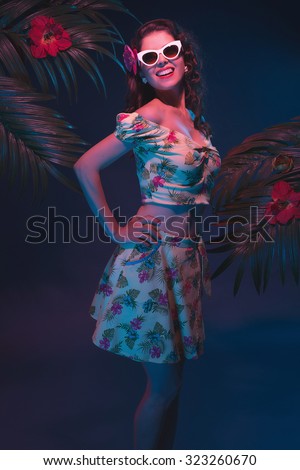 Sensual Tropical Pin-up Girl with Sunglasses in Evening Light in Front of Palm Leaves.
