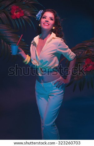 Tropical Fashion Pin-up Holding Drink with Straw in Evening Light in Front of Palm Leaves.