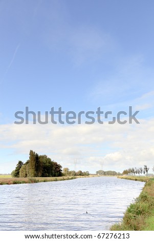 Dutch landscape with canal under cloudy sky