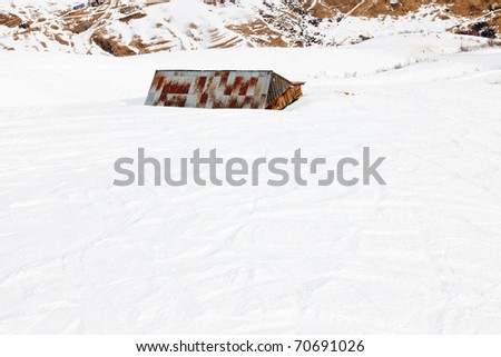 Abandoned cottage in snow winter mountain landscape. Alps. France.