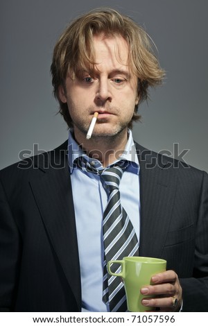 Portrait of angry young business man with cigarette and cup of coffee. Confused. Crisis.