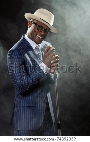 Black man with blue striped suit and blue hat singing in a smoky nightclub like a cotton club
