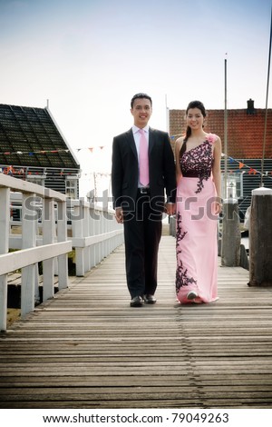 Romantic young asian couple in love walking on pier.