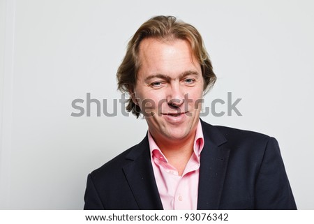 Smiling young business man with blond hair in blue suit and pink shirt isolated on white background
