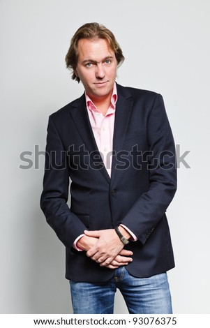 Smiling young business man with blond hair in blue suit and pink shirt isolated on white background