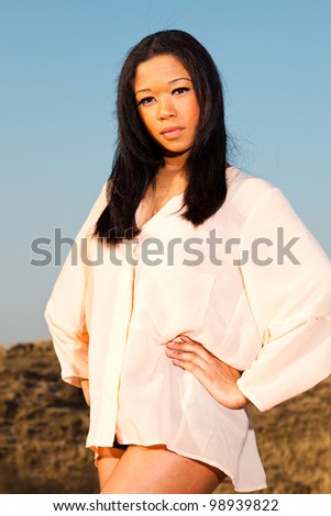 Pretty young black woman posing in dune landscape with clear blue sky. Enjoying outdoors.