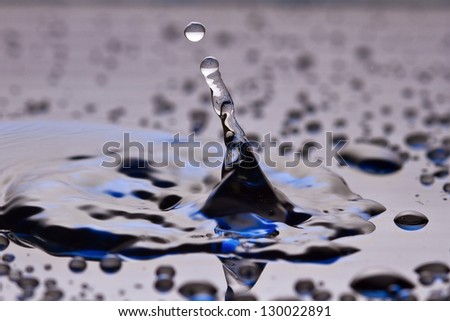 Blue and black water drop on shiny black surface