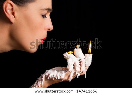 Three candle sticks on fingers burning with wax flow face blowing