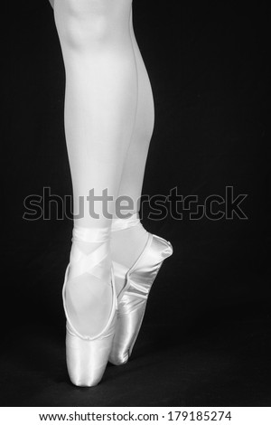 A ballet dancer standing on toes while dancing on black background artistic conversion