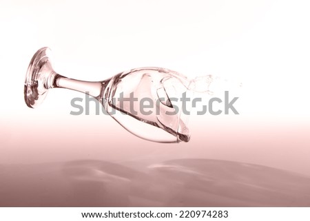 Glass with clear water falling over to spill with a peach back lighting