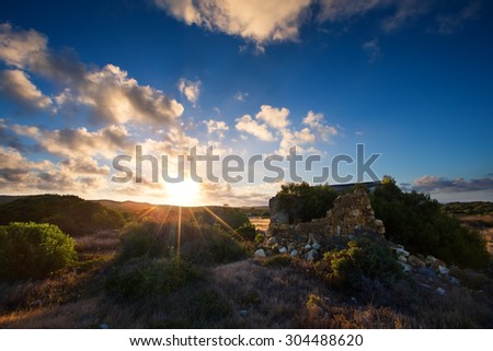 Old small deserted house in field with a cloud sunset landscape