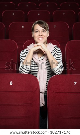 Smiling woman waiting a movie at the cinema