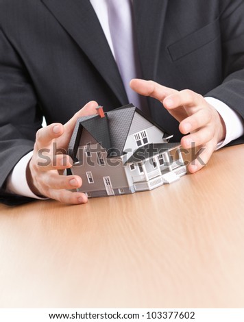 Real estate concept - business man hands around home architectural model
