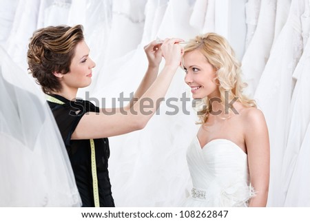 Shop assistant helps to fix the wedding tiara, white background