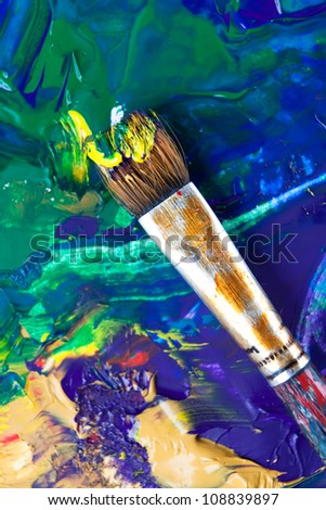 Painting some picture with paintbrush using mixture of blue, green, yellow, violet colors, white background