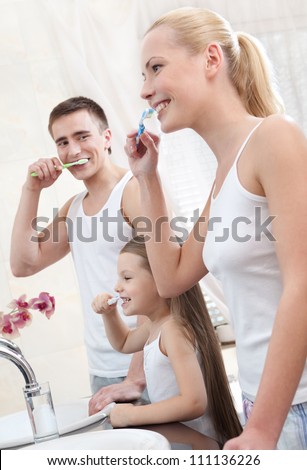 Happy family of three people brush their teeth in bathroom