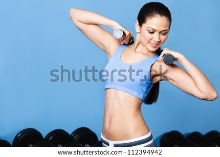 Woman works out with dumbbells in fitness gym