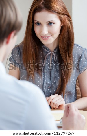 Woman talks with man sitting at the table at the cafeteria