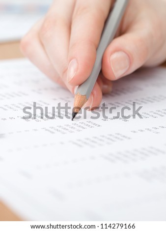 Close up view of hand making notes in the document with pencil