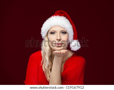 Pretty woman in Christmas cap blows kiss, isolated on purple