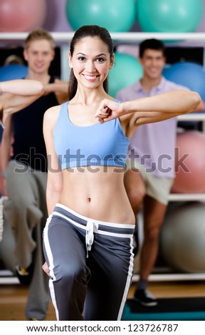 Sexy female coach works out with her group at the gym in a fitness class in order to keep fit