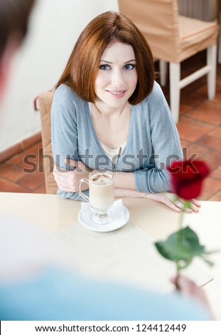 Young man presents a red rose to his girlfriend at the cafe