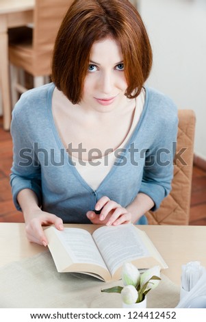 Woman reads an interesting book sitting at the cafe