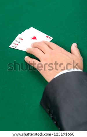 Hand with aces on the green table. Risky entertainment of gambling
