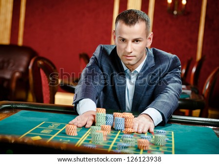 Gambler placing a bet at the roulette table at the casino. Risky entertainment of gambling