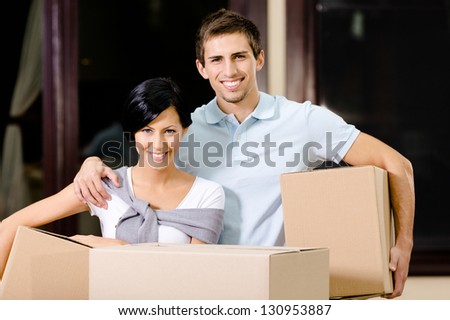 Happy couple carrying cardboard packages while moving to new house