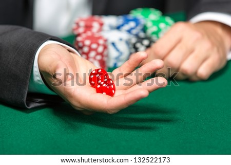 Player throws dices on the poker table. Addiction to the gambling
